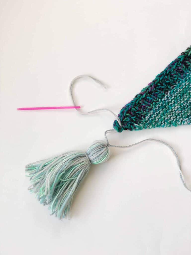 Attaching a tassel to a scarf.