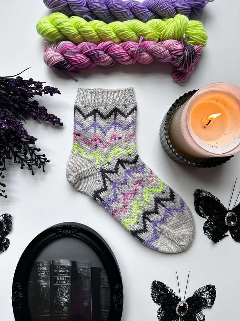 Finished Whispering Webs colorwork socks featuring colorful spider web motifs